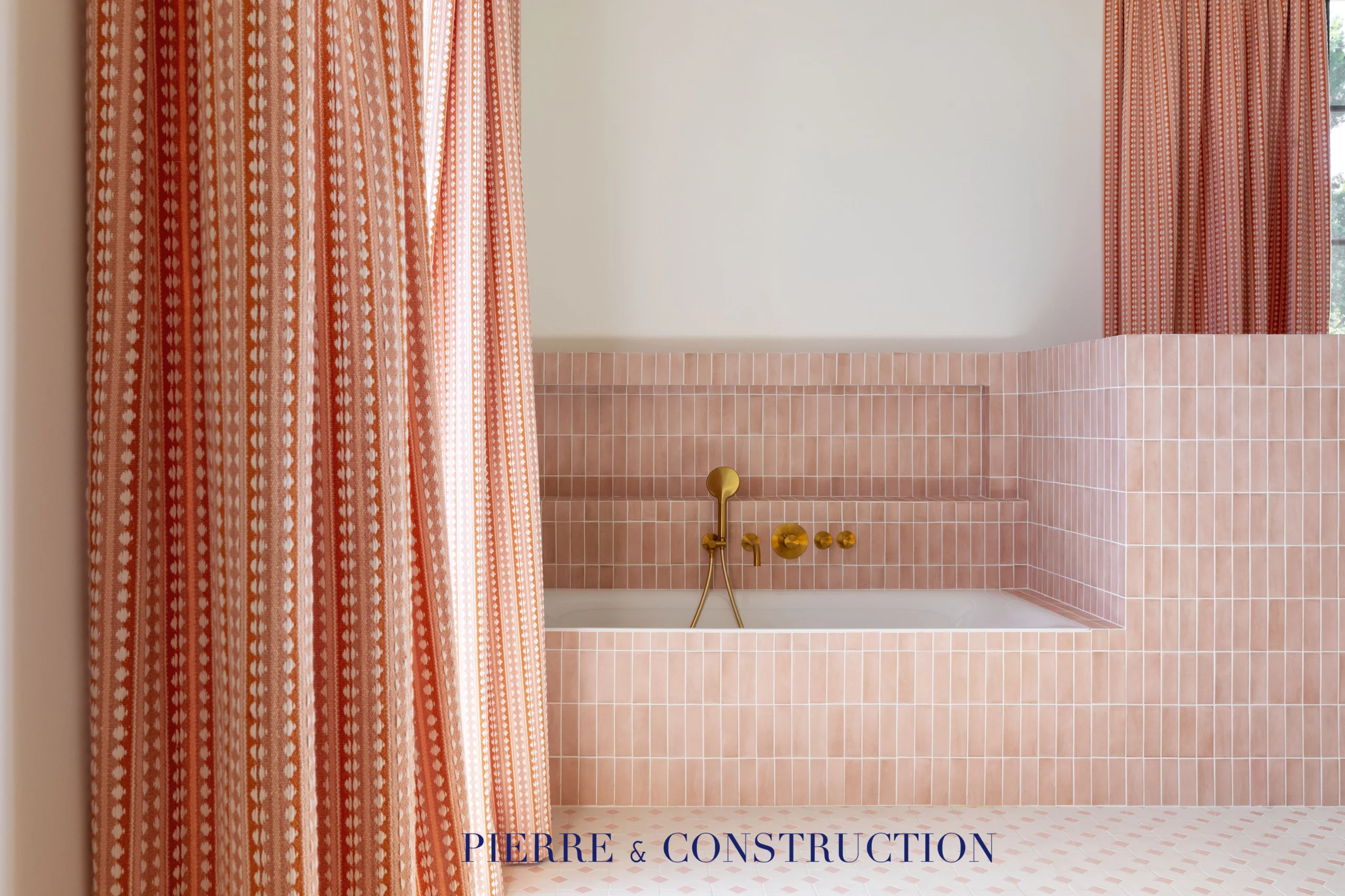 Salle de bain rose avec baignoire et robinetterie dorée dans une rénovation haut de gamme à Cannes